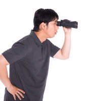 双眼鏡で観察する笑顔の男性の写真