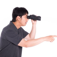双眼鏡を覗きながら観戦する男性のポートレートの写真