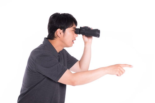 双眼鏡を覗きながら観戦する男性のポートレート