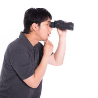 双眼鏡で何かを監視して考える男性の不可思議な行動の写真