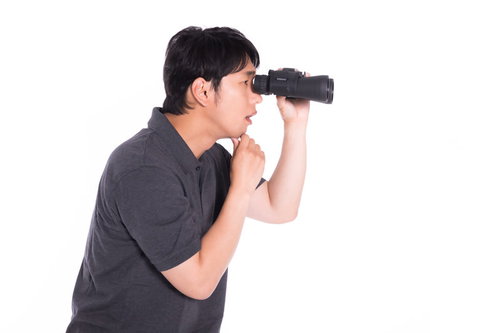 双眼鏡で何かを監視して考える男性の不可思議な行動