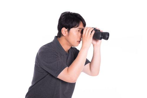 見えないものを見ようとして双眼鏡をのぞき込んだ男性