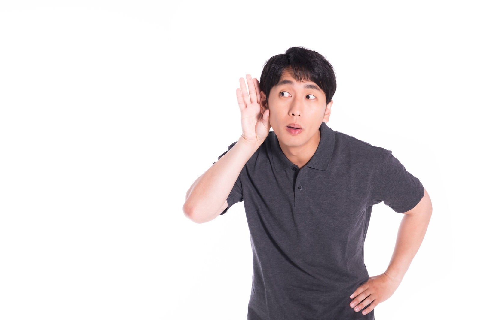 片手を耳に当てて遠くの音を聞く男性［モデル：大川竜弥］