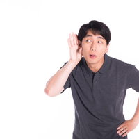 遠くの音を聞き耳を立てる男性の写真