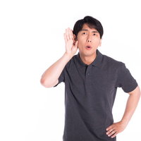 内緒話に耳を傾ける男性の驚きの表情と聴く仕草の写真