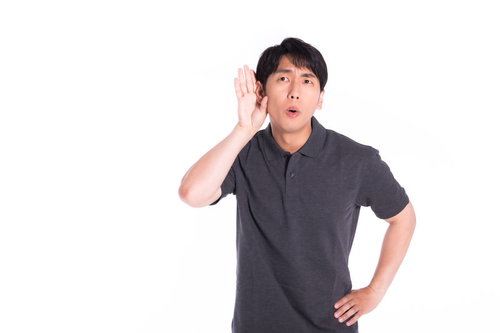 内緒話に耳を傾ける男性の驚きの表情と聴く仕草