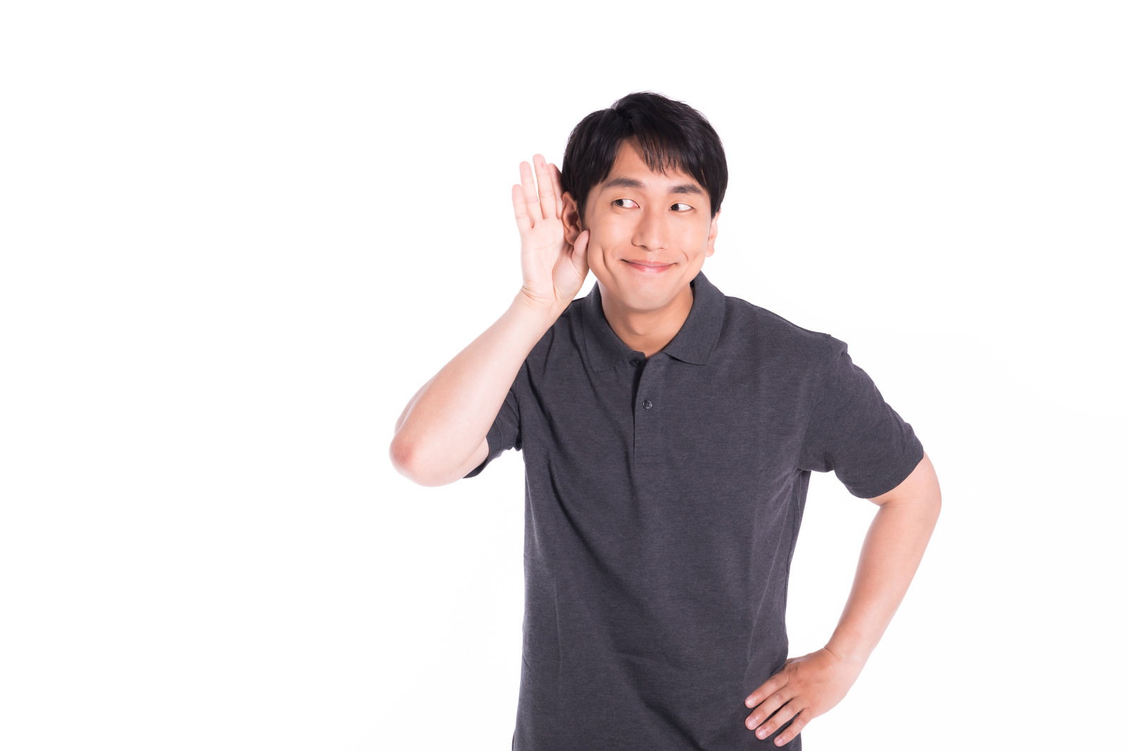手を耳に当てて聞き耳を立て、微笑んでいる男性［モデル：大川竜弥］