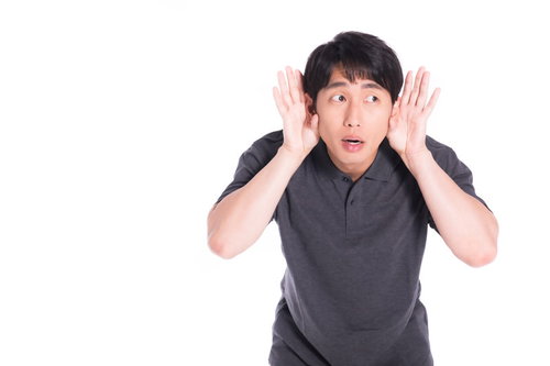 両手を耳に当てて音を聞き取ろうとする男性