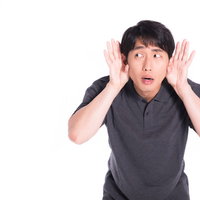 近隣住民の騒音に悩んで耳をふさぐ男性の困った表情の写真