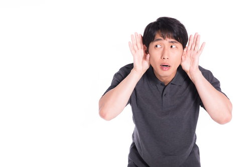 近隣住民の騒音に悩んで耳をふさぐ男性の困った表情