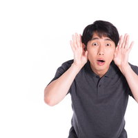 びっくりして両耳に手を当てて再度聞き直す男性の写真