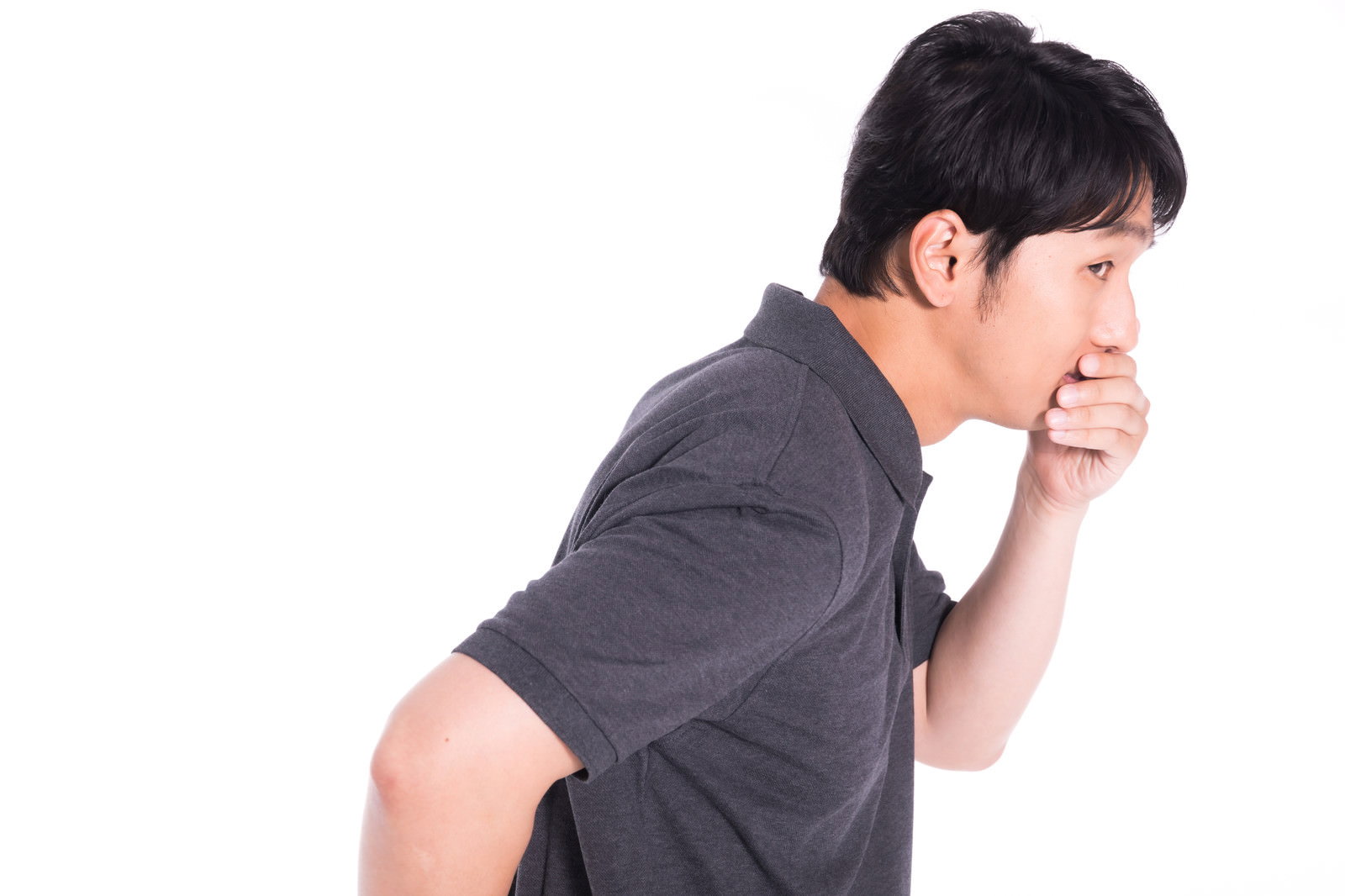 手で口を覆って驚きの表情を見せるグレーのTシャツの男性［モデル：大川竜弥］