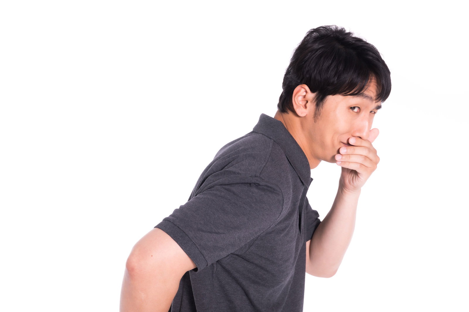 グレーのシャツを着た男性が手を口元に当ててニヤニヤ笑っている［モデル：大川竜弥］