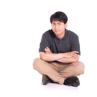 納得がいかない様子で腕を組んで座る男性のクレーム対応の写真