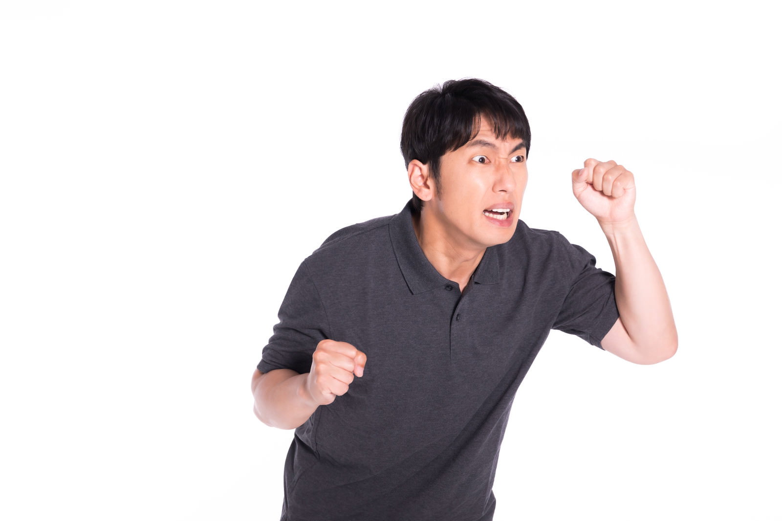 グレーのシャツを着て右手で拳を作り威嚇するポーズの男性［モデル：大川竜弥］