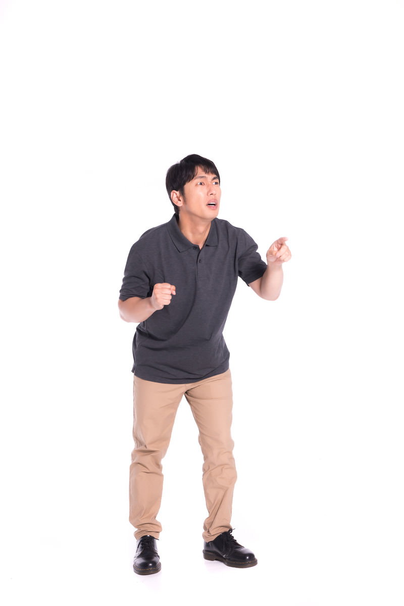 グレーのシャツを着て唖然とした表情で指を差している男性［モデル：大川竜弥］