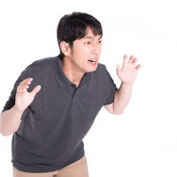 グレーのポロシャツを着た大きな声で威嚇する男性の写真