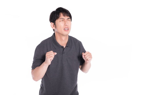 無念の表情で両手を握り締めている男性の感情表現