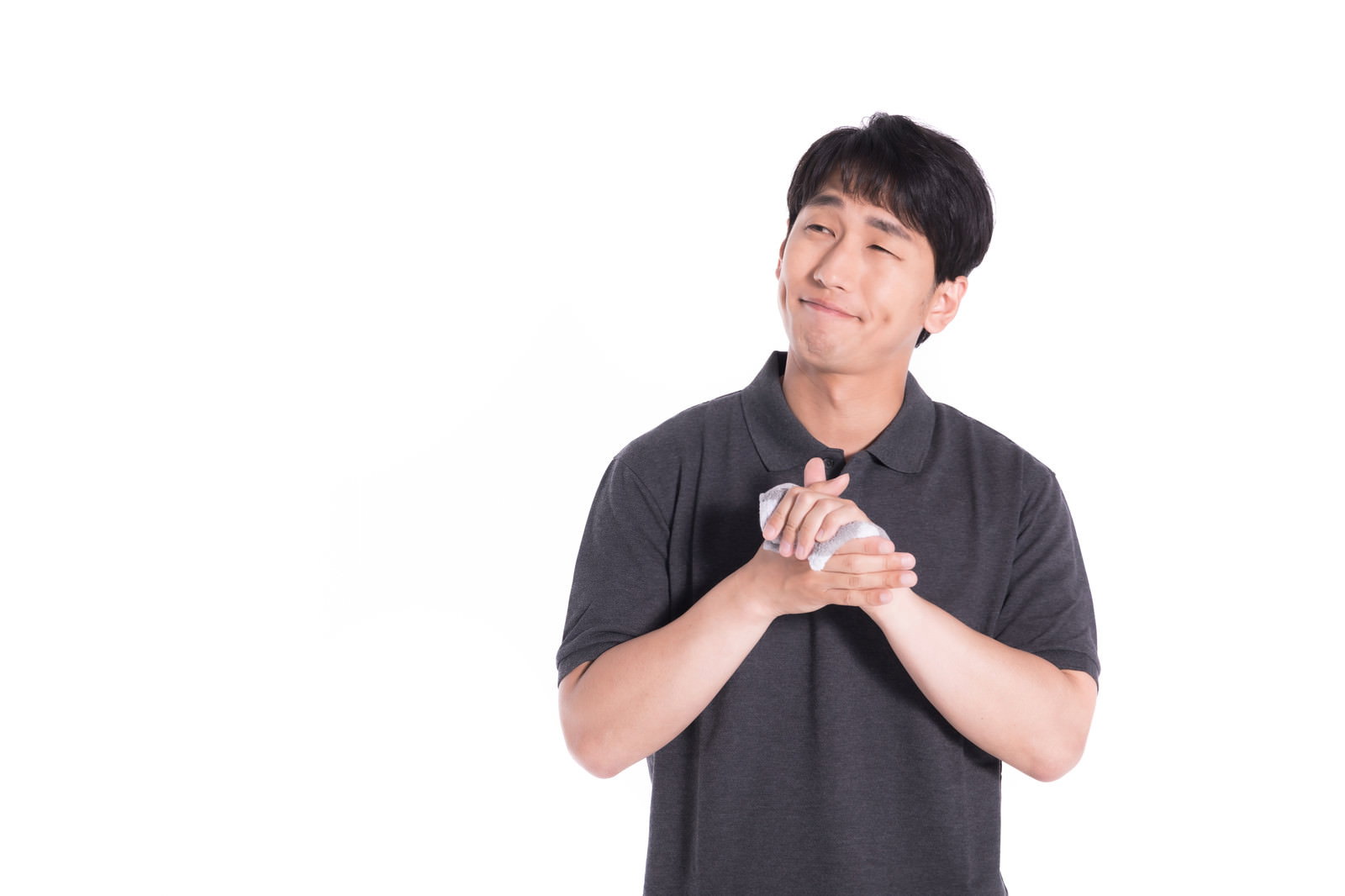 黒いTシャツを着た男性が上を見上げながら両手を胸の前で合わせている様子［モデル：大川竜弥］