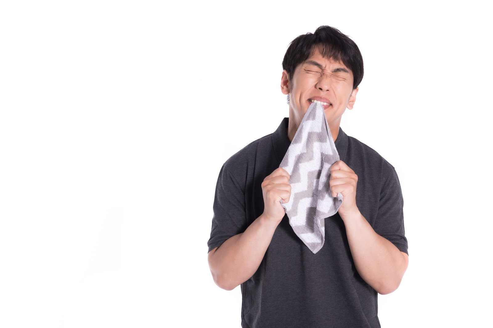 白いハンカチを両手で持ち、悔しそうに噛みしめている男性［モデル：大川竜弥］