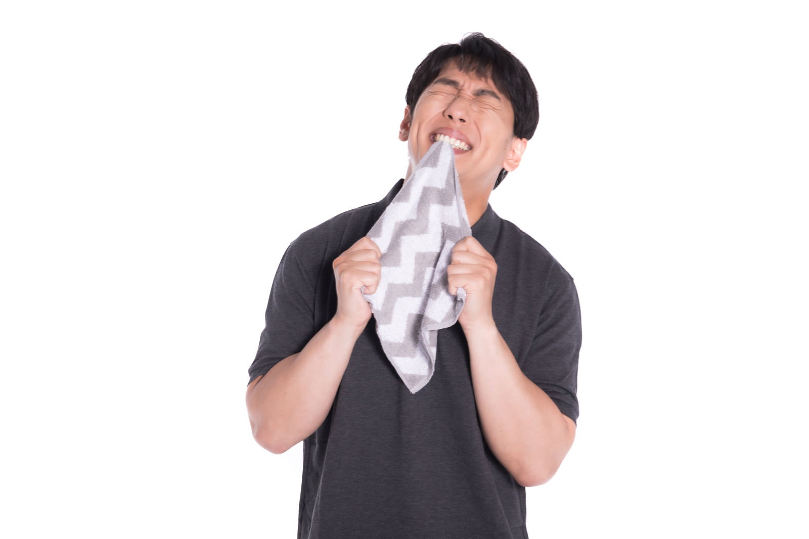 白いタオルを噛みしめて悔しがる黒いTシャツの男性［モデル：大川竜弥］