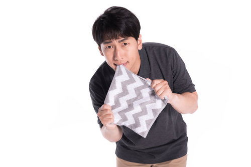 口と手でハンカチを引っ張り噛みしめる男性