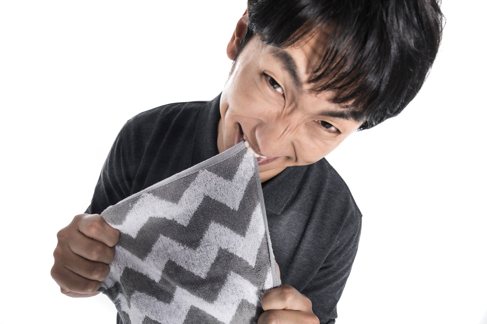 歯を噛みしめて激しく怒っている黒いスーツ姿の男性［モデル：大川竜弥］