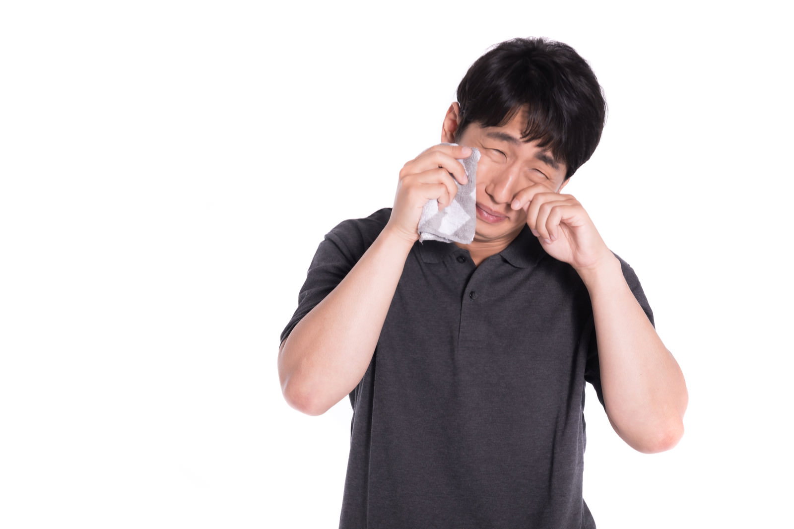 黒いTシャツを着た男性が両手で顔を覆って泣いている［モデル：大川竜弥］