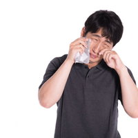 両手で顔を覆って泣く男性の笑い泣きの感情表現の写真