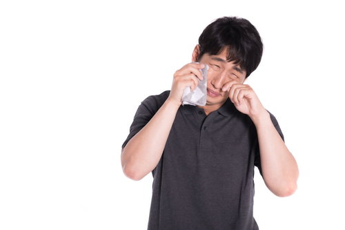 両手で顔を覆って泣く男性の笑い泣きの感情表現