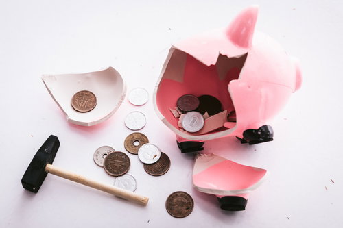 ハンマーで割られたピンクの貯金箱と散らばった硬貨