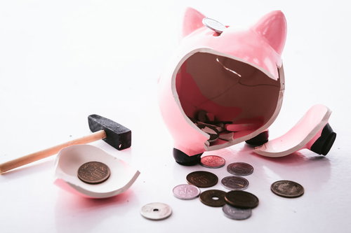 ハンマーで割られたピンク色のブタの貯金箱から出た小銭