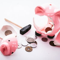 割れて硬貨が散らばったピンク色の豚の貯金箱の写真