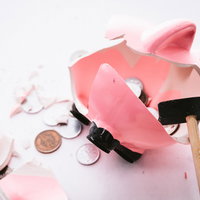 ハンマーで割ったピンク貯金箱から散らばる小銭の写真