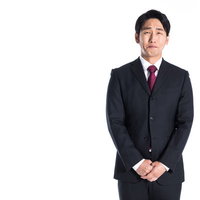 口をつぐんでじっと我慢をする黒いスーツの会社員男性の写真