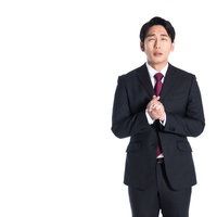 黒いスーツを着てもみ手をする営業マンの謝罪ポーズの写真