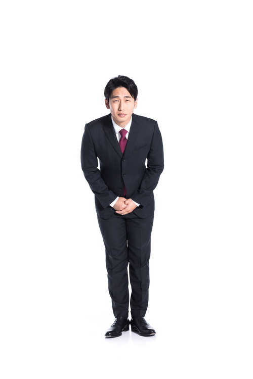 正面で深々と謝罪をする黒いスーツの会社員男性