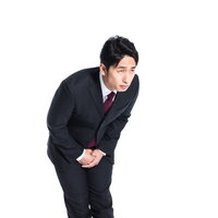 腰を深く曲げて両手を合わせた謝罪のお辞儀をする男性の写真