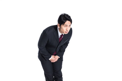 腰を深く曲げて両手を合わせた謝罪のお辞儀をする男性