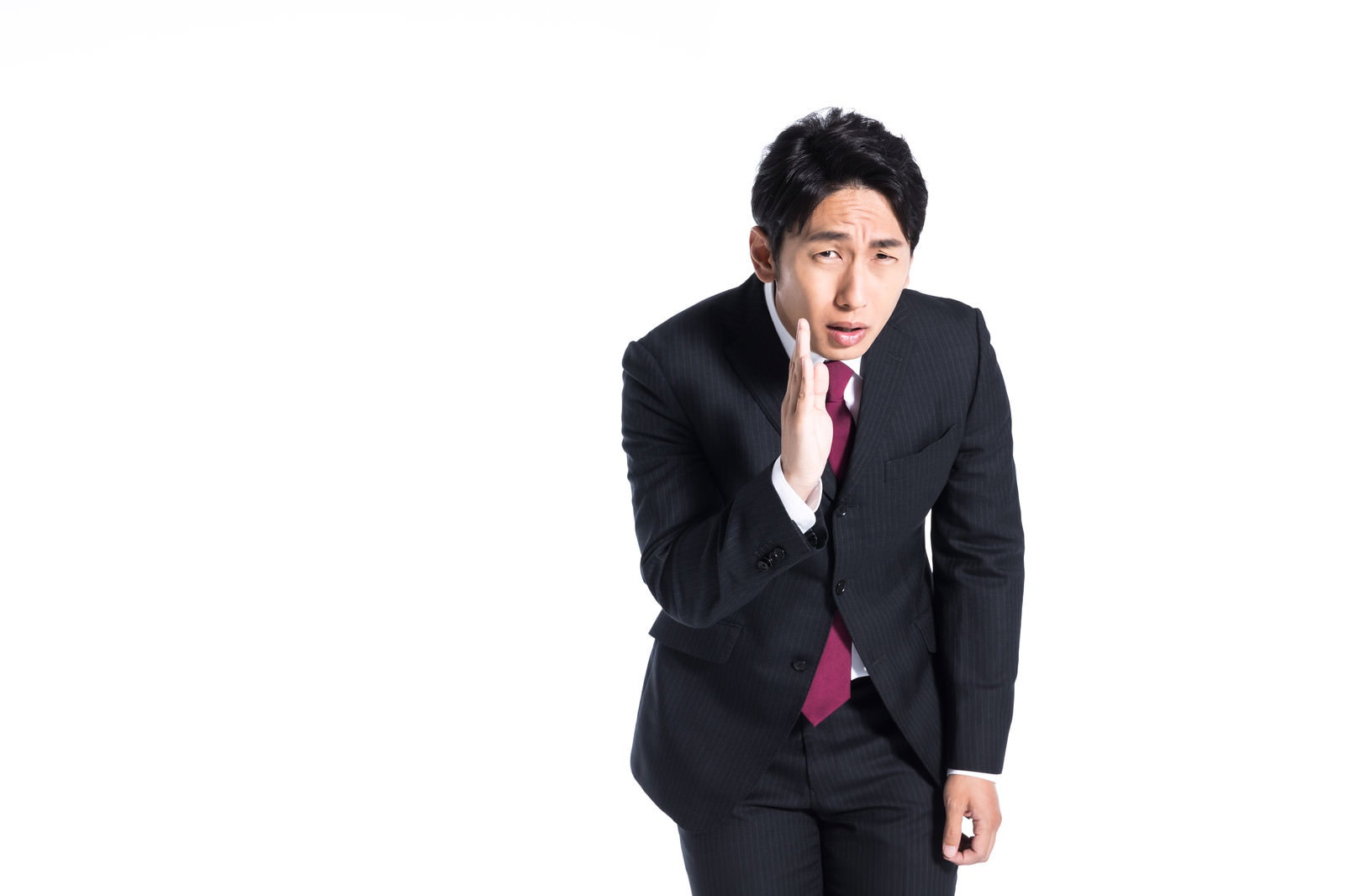 人差し指を口元に当てて内密をお願いするスーツ姿の男性［モデル：大川竜弥］