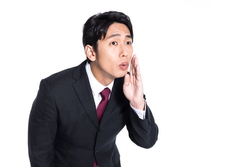 小声でデマを流すスーツの男性