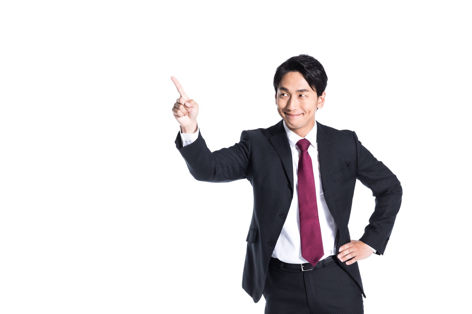 スーツを着た営業マンが片手を腰に当て指を立てて満足そうに笑顔を見せている［モデル：大川竜弥］