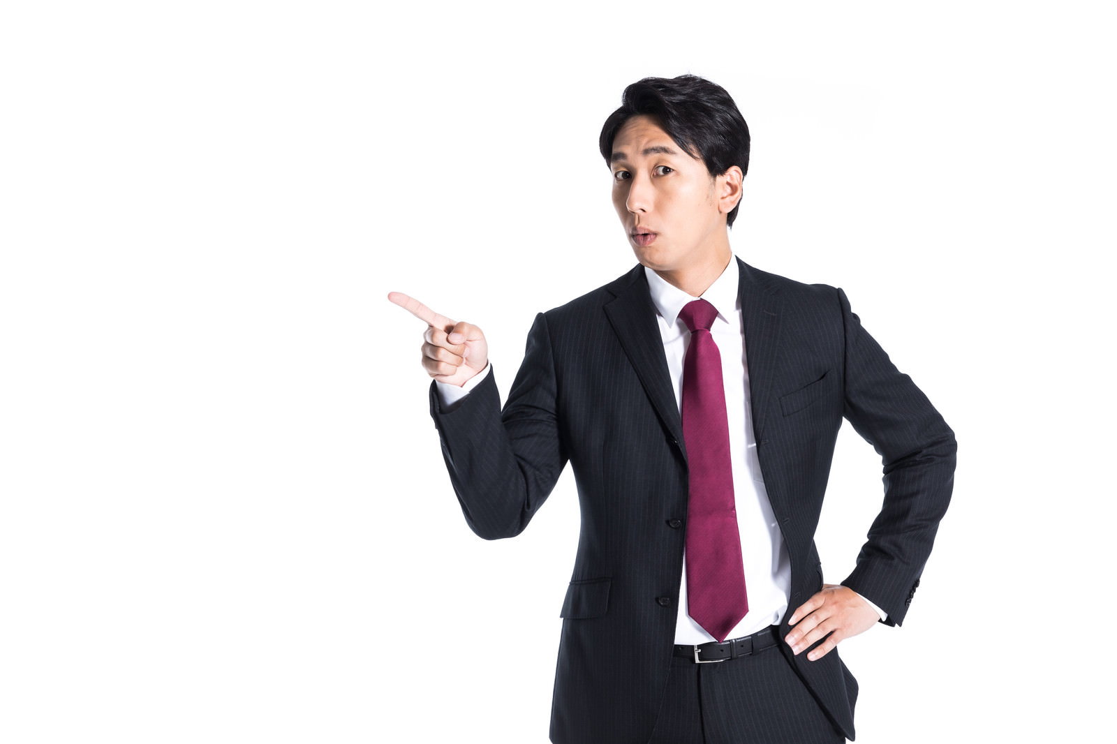 指差しポーズをする紺色スーツに赤いネクタイの男性会社員［モデル：大川竜弥］