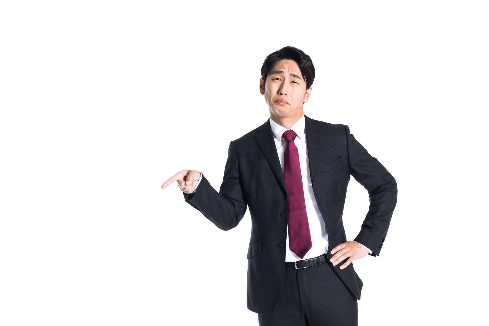 紺色のスーツを着た男性が右手で指差しをしながら不満そうな表情をしている［モデル：大川竜弥］