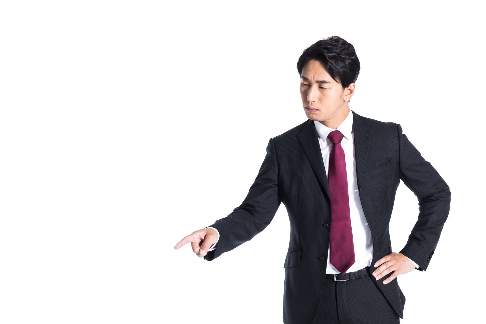 左下を指さす紺色のスーツに赤いネクタイの会社員男性［モデル：大川竜弥］