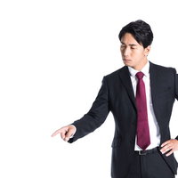 左下を指さす紺色スーツの会社員、下落傾向を説明の写真