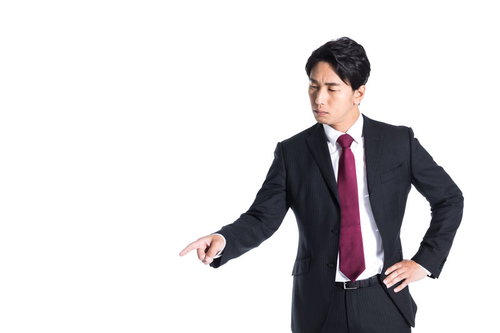 左下を指さす紺色スーツの会社員、下落傾向を説明