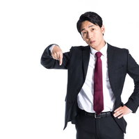 下を指さすスーツ姿の会社員男性のビジネスポーズの写真