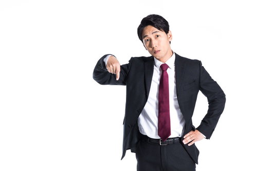 下を指さすスーツ姿の会社員男性のビジネスポーズ