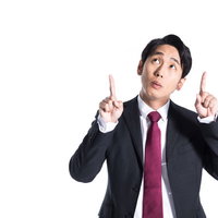 疑問に感じるポイントを上部で指差すスーツ姿の男性の写真